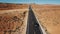 Drone following silver car on empty desert highway road in Arizona, camera tilts up to reveal flat landscape and skyline