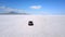 Drone following silver minivan car driving towards mountains in the middle of breathtaking Bonneville salt lake desert.