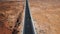 Drone following and zooming in on silver car driving along sunny American desert landscape on empty highway road.