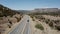 Drone follows silver minivan car driving on majestic sunny desert hills road in summer Arizona, USA. Road trip vacation.