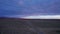 Drone footage of asphalt highway winding through vast open fields during cloudy sunset in California