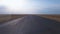 Drone footage flying over deserted road in the middle of harvested agricultural fields, rapidly gaining speed and