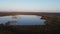 Drone footage over a man-made lake from the mining area around the town of Kajaani at sunset. View of tundra and Finnish forests f