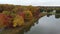 Drone footage of small lake in natural landscape with colorful trees in autumn