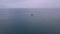 Drone footage: Tourist boat ascending in the serene blue ocean towards horizon.