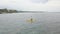 Drone footage: A young woman kayaking in the ocean in a tropical resort.