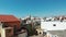 Drone goes up in cyprus city paphos with orange tree ahead and city buildings with red rooftops. Aerial view