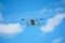 a drone with a high-resolution digital camera flies against a blue sky with clouds