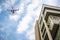 Drone with high resolution digital camera flying over city . An aerial view of a flying multi-copter with raised landing gears and