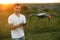 Drone hovers in front of man with remote controller in his hands. Quadcopter flies near pilot. Guy taking aerial photos