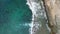 Drone landscape flyover splashing turquoise sea waves by rocky coastline