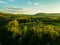 Drone landscape over lush farm fields and green dense forest under sunset sky in Pennsylvania