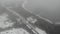 Drone moving down thru fog cloud and snow. Winter road, coast of lake gulf. Pier