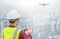 Drone operated by construction worker on building site. Construction worker piloting drone at building site with cityscape backgro