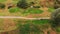 Drone outdoor shot of a group of people standing near a dirt road on a golf course, having fun playing the game in a