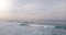 Drone panning left to reveal epic sunset above high foaming waves in beautiful open ocean. Amazing seascape panorama.