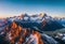 Drone perspective of mountain peaks glowing at sunrise, wide aerial panorama. AI generated.