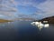 Drone photo of a sailboat moored in a shallow bay near several grounded icebergs in western Greenland