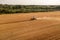 Drone photography of farmer with a combine harvesting a yellow agriculture grain field