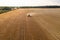 Drone photography of farmer with a combine harvesting a yellow agriculture grain field