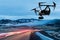 drone quad copter with a camera flies over a road with car light