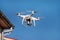 Drone quad copter fly on blue sky in background. Modern drone is flying in air, to take photos and record footage from above.