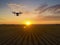 Drone quad copter on green field. Drone flying over the hills with the beautiful sunset