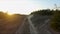 Drone racing view. Fly over dust road in forest at sunset. Dynamic shot