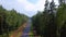 The drone rises above the wet road and dense forest.