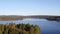 Drone rises from Kielder forest canopy to reveal Kielder lake at sunrise with big blue skies.