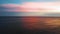 Drone rising footage over the golden seawater waves under the pink cloudy sky of sunset