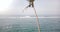 Drone rising from the ground above amazing sunny ocean foaming waves panorama to reveal a single palm tree with coconuts