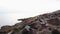 Drone shooting a close-up of a lighthouse on a hill by the sea and a group of people walking