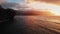 Drone shoots purple sunset over the waves, black mountains in the clouds on the horizon Kauai, Hawaii, USA