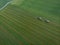 Drone shot of agricultural field with tractors harvesting hay