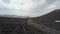 Drone shot of cars and bicycles moving by a road among vineyards on black volcanic soil in Lanzarote. Aerial scenic view