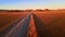 Drone shot from front of suv travelling through african desert. Aerial view of car with tourists moving through orange