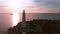 Drone shot lighthouse beach lighthouse sunset. Lighthouse on a background of beautiful sunset.