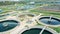 Drone shot of round sedimentation tanks at a wastewater treatment plant in daylight. Water management concept.