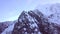 Drone shot slowly orbiting a craggy and jagged alpine mountain peak in winter