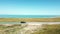 Drone shot of a SUV running on lake side road under blue sky