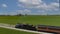 Drone Side View of a Antique Steam Passenger Train Approaching Around a Curve Thru Fertile Farmlands