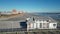 Drone slide view of people walking on wooden pier with a large deserted beach in the background