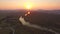 DRONE: Sunrise shines on the tranquil river flowing past the calm countryside.