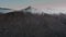 Drone swirls over snow-capped mountains, a dense forest and a mirror lake at sunset at Eklutna Lake, Alaska, USA