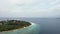 Drone tilt up over small island, Maldives atoll and Indian Ocean with skyline