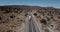 Drone tilts down over large delivery truck moving along beautiful sandstone desert hill road in hot summer Arizona, USA.