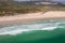 Drone top aerial view above surfer surfing on paradise turquoise sea water crashing waves, in Spain