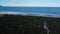 Drone traveling through the lagoon, passing through vegetation and arriving at the beach, showing the horizon.