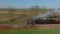 Drone Traveling Parallel View of a Steam Passenger Train Blowing Lots of Smoke and Steam